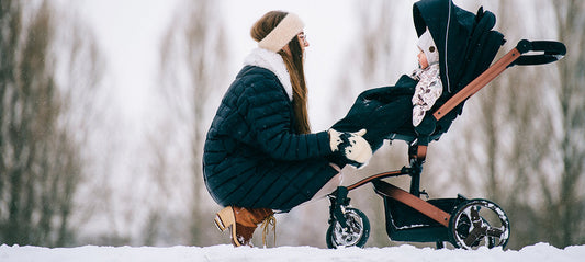 Mom with baby in the stroller in the snow