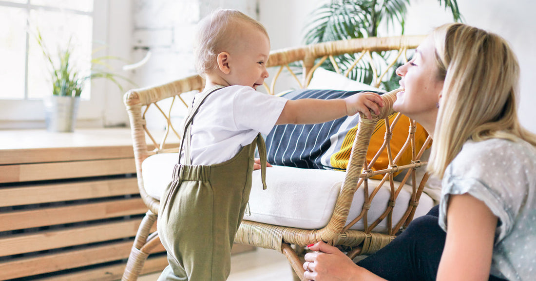 Toddler walks smiling towards a woman.