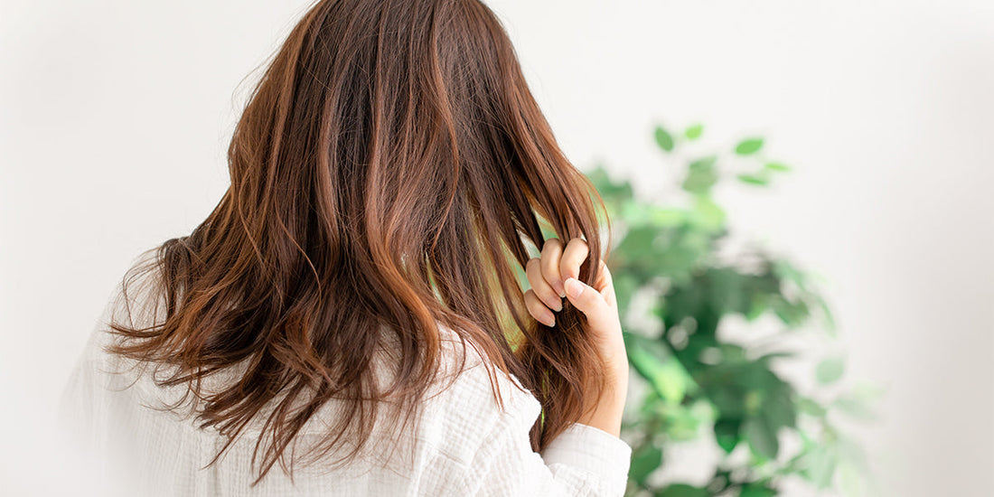 Woman from behind visible, runs her fingers through her hair