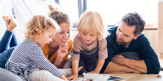 Mother and father are reading something to their two little children.