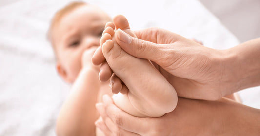 Baby is getting his foot massaged by the osteopath.