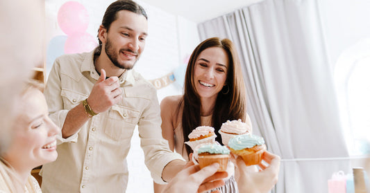 Couple celebrating a gender reveal party with cupcakes with friends.