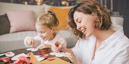 Mother is crafting paper hearts with her daughter.