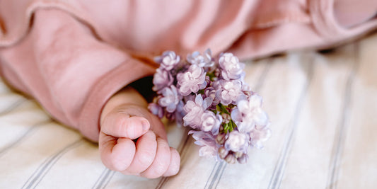 Baby is lying on the bed with a bunch of flowers
