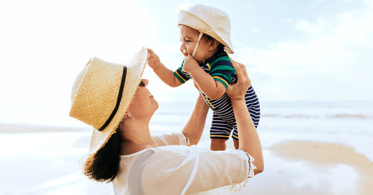 Mother with baby wearing a sun hat at the beach.