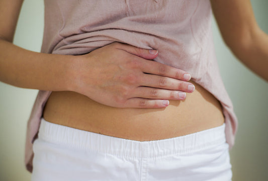 Young woman touches her stomach.