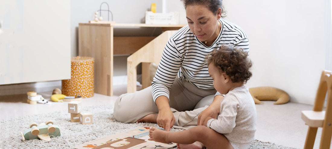 Mother and child are sitting together on the child's room floor and playing.