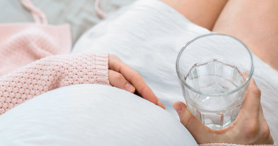 Pregnant woman holding a glass of water.