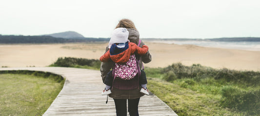 Mother carries her baby in the carrier on her back.