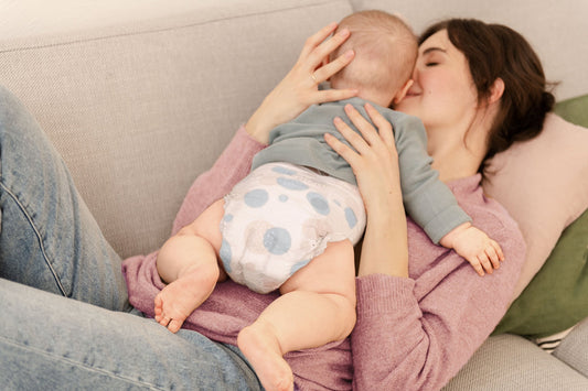 Mom lying on a sofa cuddling her baby