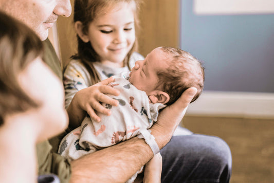 Family holding their baby in their arms and sister beside them