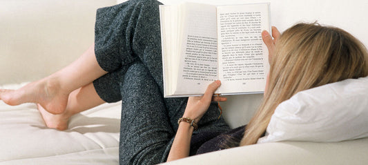 young woman lying on the sofa reading a book