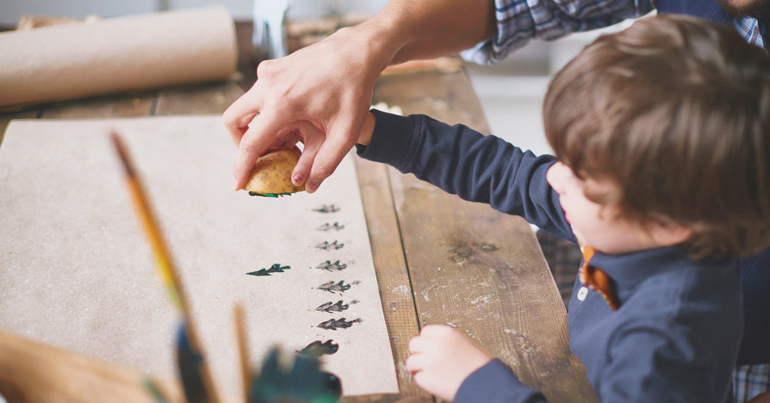 A little boy is crafting with his father for Christmas using potato stamping.
