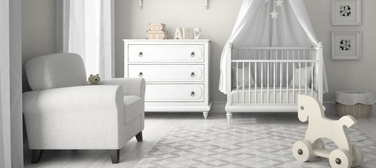 Baby room in white with baby bed, armchair, dresser, and rocking horse.