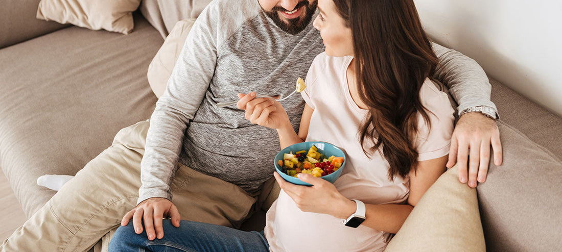 pregnant woman eating on the sofa with her partner