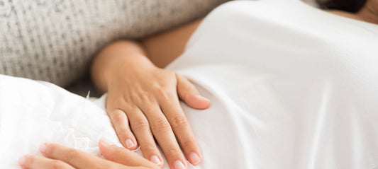 Woman lying down with both hands on her stomach