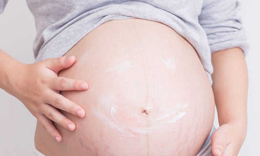 Pregnant woman applying cream on her belly