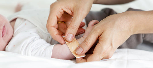Mom sticking a bandage on her baby's arm