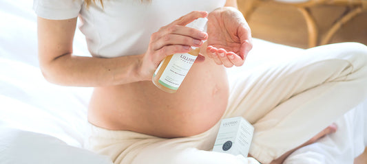 Pregnant woman applies stretch mark oil