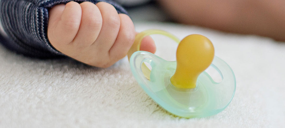 Baby hand next to a pacifier.