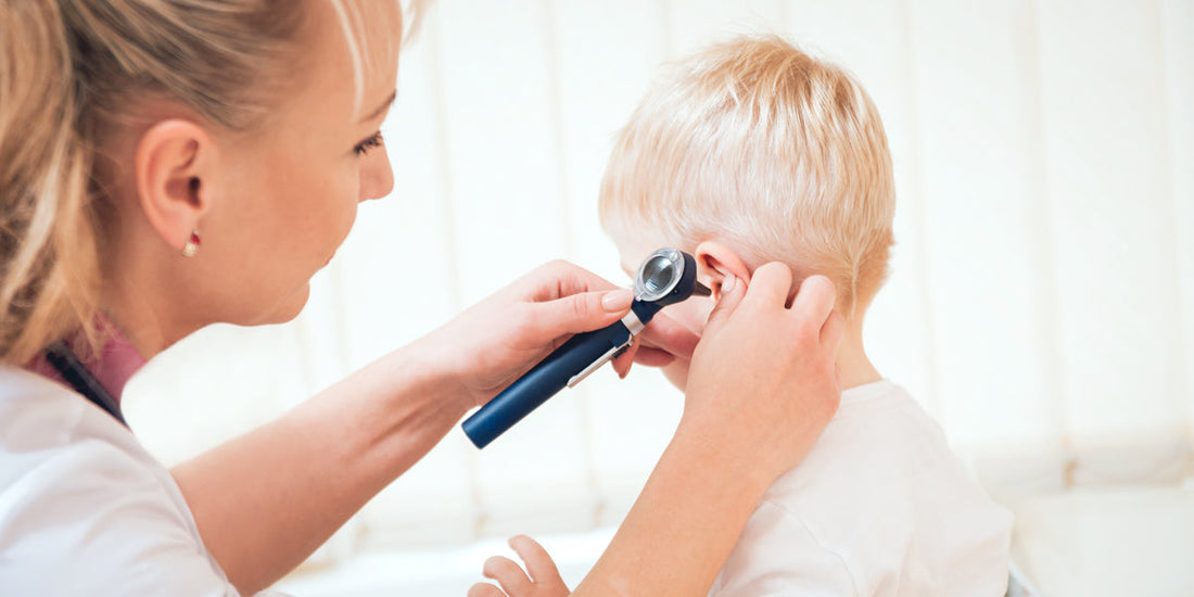 Toddler is being examined by a doctor with an otoscope at the ear.