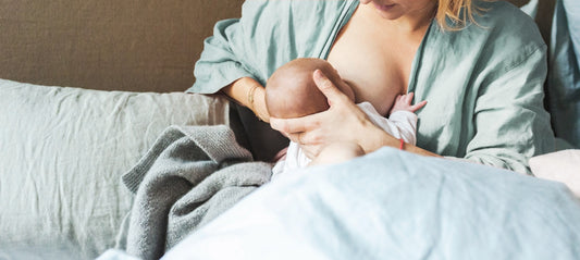 New mother is breastfeeding her baby on the bed