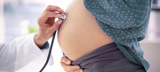 Doctor examines the abdomen of a pregnant woman during a check-up with a stethoscope