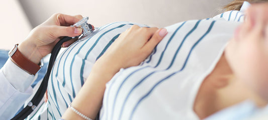 Doctor examines the pregnant woman's abdomen with a stethoscope for contractions