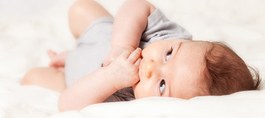Teething baby biting his hand